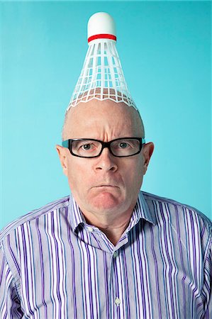 Portrait of angry man with shuttlecock on head over colored background Fotografie stock - Premium Royalty-Free, Codice: 693-06323938