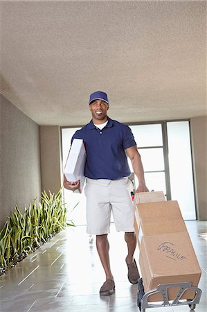 delivery man delivering boxes - Happy African American delivery man with packages Stock Photo - Premium Royalty-Free, Code: 693-06323975