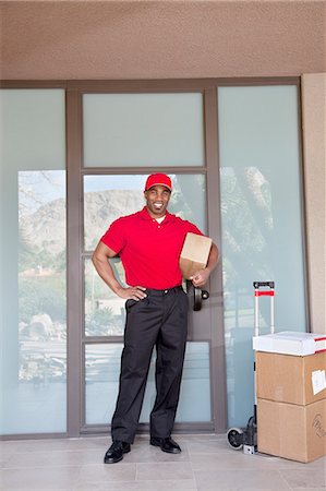 delivery man delivering boxes - Portrait of a happy young delivery man standing with packages Stock Photo - Premium Royalty-Free, Code: 693-06323990