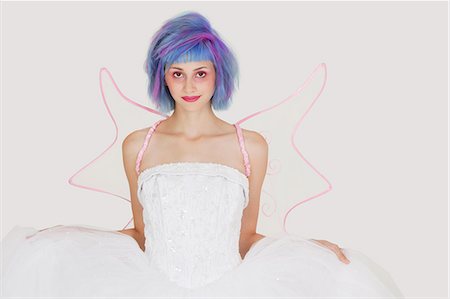 simsearch:693-06379524,k - Portrait of beautiful young woman dressed as angel with dyed hair against gray background Foto de stock - Royalty Free Premium, Número: 693-06378807