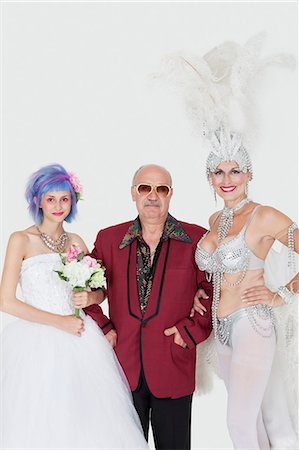 Portrait of man standing arms in arms with senior showgirl and daughter in wedding dress over gray background Stock Photo - Premium Royalty-Free, Code: 693-06378824