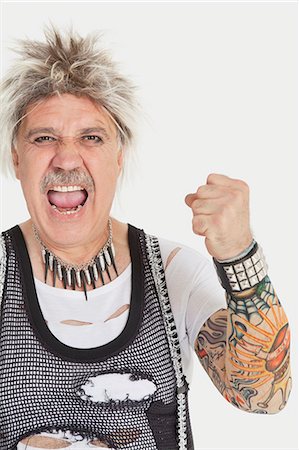 Portrait of senior male punk screaming with clenched fist over gray background Foto de stock - Sin royalties Premium, Código: 693-06378855