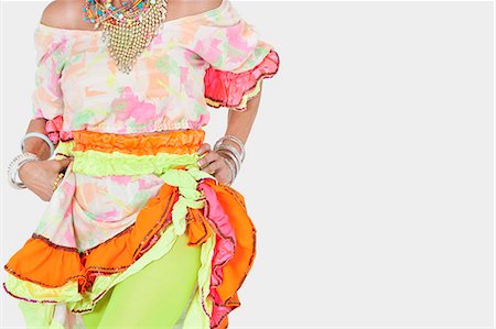Midsection of senior woman in Brazilian costume over gray background Stock Photo - Premium Royalty-Free, Code: 693-06378873
