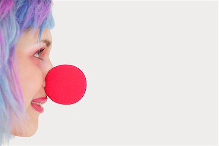 Profile of woman with red clown nose over gray background Stock Photo - Premium Royalty-Free, Code: 693-06378885