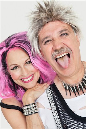 Portrait of senior punk couple with man sticking out tongue over gray background Stock Photo - Premium Royalty-Free, Code: 693-06378894