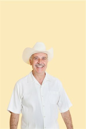 simsearch:693-06378948,k - Portrait of happy senior man wearing cowboy hat over yellow background Foto de stock - Royalty Free Premium, Número: 693-06378923