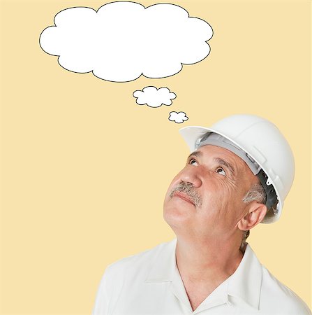 Senior construction worker with hardhat looking up over yellow background Stock Photo - Premium Royalty-Free, Code: 693-06378931