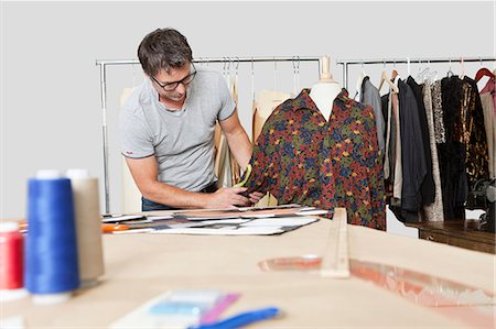 Mature male fashion designer taking measurement of shirt in design studio Foto de stock - Sin royalties Premium, Código: 693-06378995