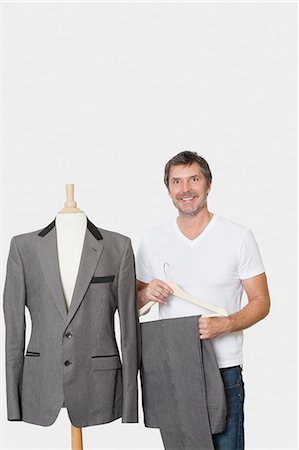 people in business suit standing - Portrait of mature man standing next to tailor's dummy over gray background Stock Photo - Premium Royalty-Free, Code: 693-06379002