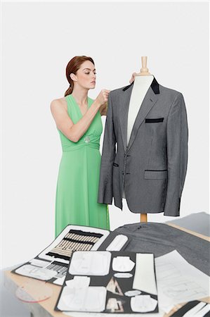 simsearch:693-06378979,k - Female designer adjusting coat on tailor's dummy over gray background Stock Photo - Premium Royalty-Free, Code: 693-06379031