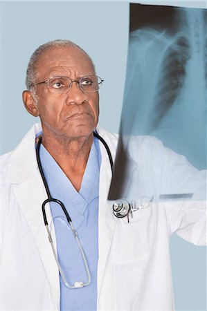 senior man african american - African American senor doctor analyzing x-ray report over light blue background Stock Photo - Premium Royalty-Free, Code: 693-06379044