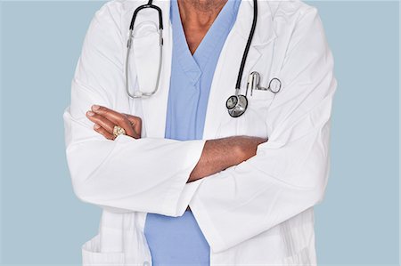 simsearch:693-06379058,k - Midsection of a doctor with arms crossed over light blue background Foto de stock - Sin royalties Premium, Código: 693-06379046