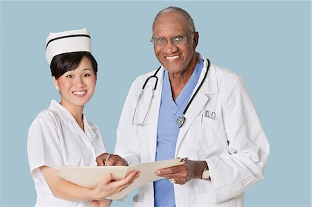 senior asian male doctor with stethoscope - Portrait of happy health care professionals with medical report over light blue background Stock Photo - Premium Royalty-Free, Code: 693-06379050