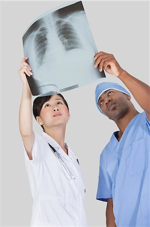 doctor looking at xray - Male surgeon with nurse examining x-ray report over gray background Stock Photo - Premium Royalty-Free, Code: 693-06379063