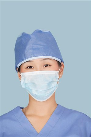 doctor with cap and mask - Close-up of a female surgeon wearing facemask over light blue background Stock Photo - Premium Royalty-Free, Code: 693-06379077