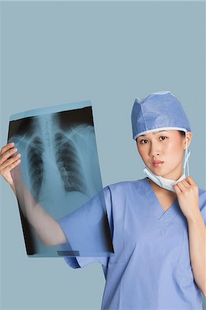 female doctor cap - Portrait of a female surgeon holding x-ray report over light blue background Stock Photo - Premium Royalty-Free, Code: 693-06379080