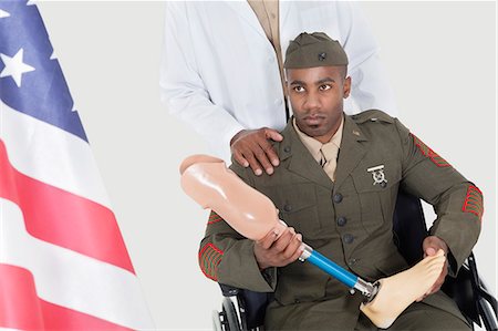 senior man african american - Doctor with disabled military officer holding artificial limb as he looks at American flag Stock Photo - Premium Royalty-Free, Code: 693-06379091