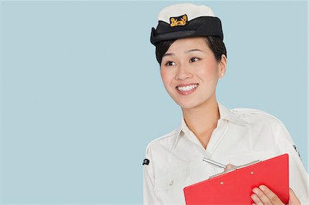 soldat - Heureuse femme officier de marine américaine avec presse-papiers souriant sur fond bleu clair Photographie de stock - Premium Libres de Droits, Code: 693-06379117