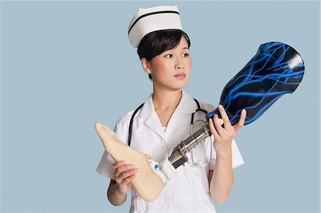 simsearch:693-06379116,k - Female doctor holding prosthesis foot over light blue background Foto de stock - Sin royalties Premium, Código: 693-06379126