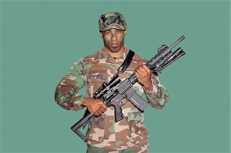 soldier standing with gun - Portrait of a young, African American soldier with M4 assault rifle, studio shot on green background Stock Photo - Premium Royalty-Free, Code: 693-06379154