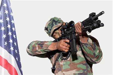 Soldier aiming M4 assault rifle with American flag, Studio Shot on gray background Foto de stock - Sin royalties Premium, Código: 693-06379156