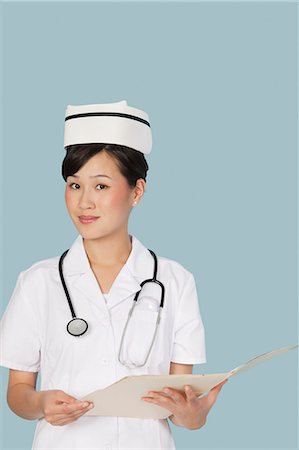 southeast asian instruments - Portrait of an attractive doctor with medical report over light blue background Stock Photo - Premium Royalty-Free, Code: 693-06379177