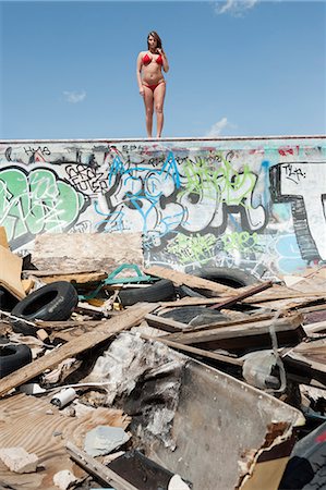 Young woman in bikini standing on graffiti wall with garbage in foreground Foto de stock - Sin royalties Premium, Código: 693-06379187