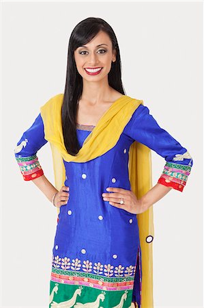 Portrait of pretty Indian woman in traditional wear standing with hands on hips over gray background Stock Photo - Premium Royalty-Free, Code: 693-06379296