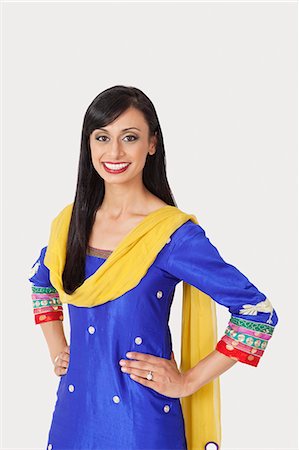 simsearch:693-06379274,k - Portrait of beautiful Indian woman in traditional wear standing with hands on hips over gray background Fotografie stock - Premium Royalty-Free, Codice: 693-06379297