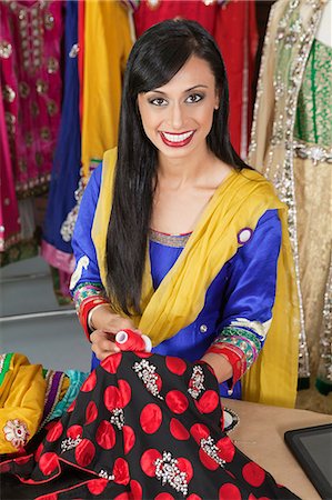 Portrait of an Indian female dressmaker matching thread color with the cloth Stock Photo - Premium Royalty-Free, Code: 693-06379315