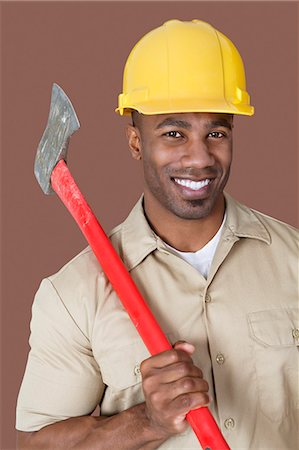 Portrait of young African man holding axe on shoulder over colored background Stock Photo - Premium Royalty-Free, Code: 693-06379318