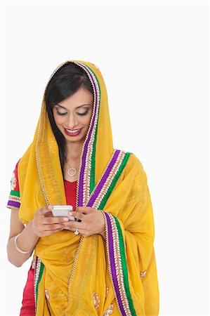simsearch:693-06435808,k - Femme indienne en vêtements traditionnels à l'aide de téléphone portable sur fond blanc Photographie de stock - Premium Libres de Droits, Code: 693-06379327