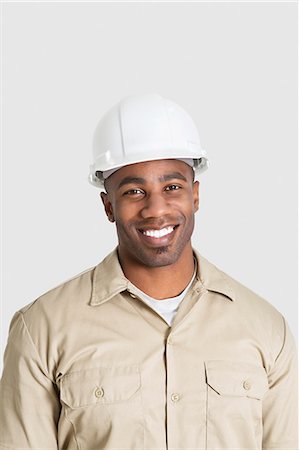 Portrait of happy young African male construction worker over gray background Stock Photo - Premium Royalty-Free, Code: 693-06379322