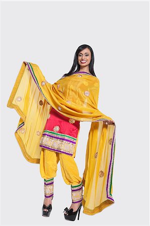 Full length of an Indian woman in salwar kameez standing over gray background Stock Photo - Premium Royalty-Free, Code: 693-06379344