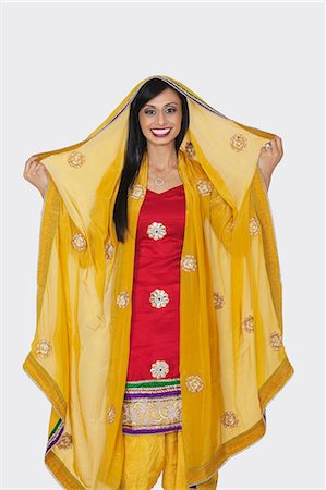 sonrisa sardónica - Portrait of beautiful Indian woman in salwar kameez standing over gray background Foto de stock - Sin royalties Premium, Código: 693-06379341