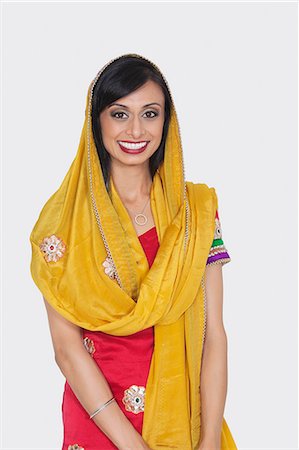 Portrait of an attractive Indian female in traditional wear standing over gray background Stock Photo - Premium Royalty-Free, Code: 693-06379343