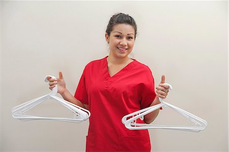 simsearch:693-06379358,k - Portrait of female housekeeper holding white plastic hangers against gray background Foto de stock - Sin royalties Premium, Código: 693-06379355