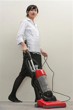 Full length of young female housekeeper vacuuming Foto de stock - Sin royalties Premium, Código: 693-06379357