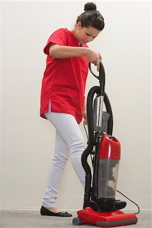 Full length of female housekeeper using vacuum cleaner Stock Photo - Premium Royalty-Free, Code: 693-06379358