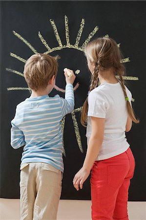 people holding chalkboards in pictures - Back view of siblings drawing sun on blackboard Stock Photo - Premium Royalty-Free, Code: 693-06379383