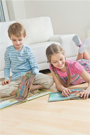 Siblings reading story books on floor in the living room Stock Photo - Premium Royalty-Free, Code: 693-06379401