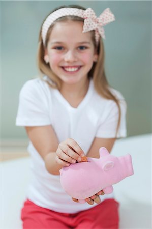 piggy bank - Portrait of a happy girl putting coin in piggy bank Stock Photo - Premium Royalty-Free, Code: 693-06379428