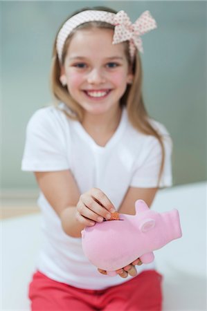 preteen girl - Portrait of a happy girl putting coin in piggy bank Stock Photo - Premium Royalty-Free, Code: 693-06379428