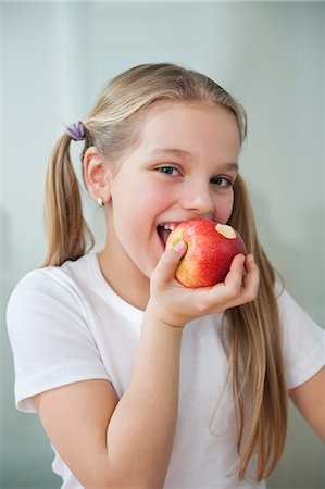 Portrait d'heureuse jeune fille mange une pomme sur fond gris Photographie de stock - Premium Libres de Droits, Code: 693-06379436