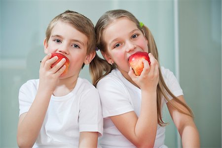 dieta sana - Portrait of young boy and girl in white tshirts eating apples Foto de stock - Sin royalties Premium, Código: 693-06379438