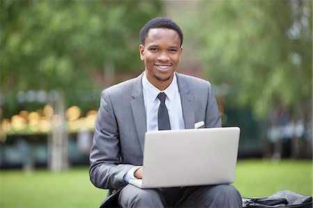 simsearch:693-06379459,k - Portrait of a happy African American businessman using laptop in park Stock Photo - Premium Royalty-Free, Code: 693-06379458