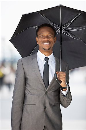 simsearch:693-06379459,k - Portrait of a happy African American businessman holding umbrella Stock Photo - Premium Royalty-Free, Code: 693-06379460