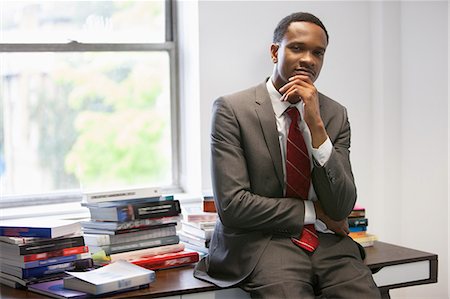 simsearch:693-06379459,k - Portrait of a confident African American businessman sitting on office desk Stock Photo - Premium Royalty-Free, Code: 693-06379478