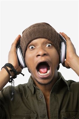 Portrait of a surprised young African American man listening music through headphones Stock Photo - Premium Royalty-Free, Code: 693-06379484