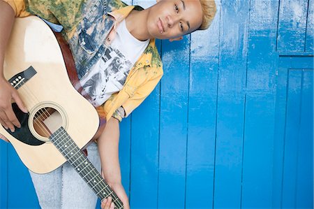 Portrait d'un garçon adolescent jouer de la guitare contre le bois à panneaux muraux Photographie de stock - Premium Libres de Droits, Code: 693-06379489
